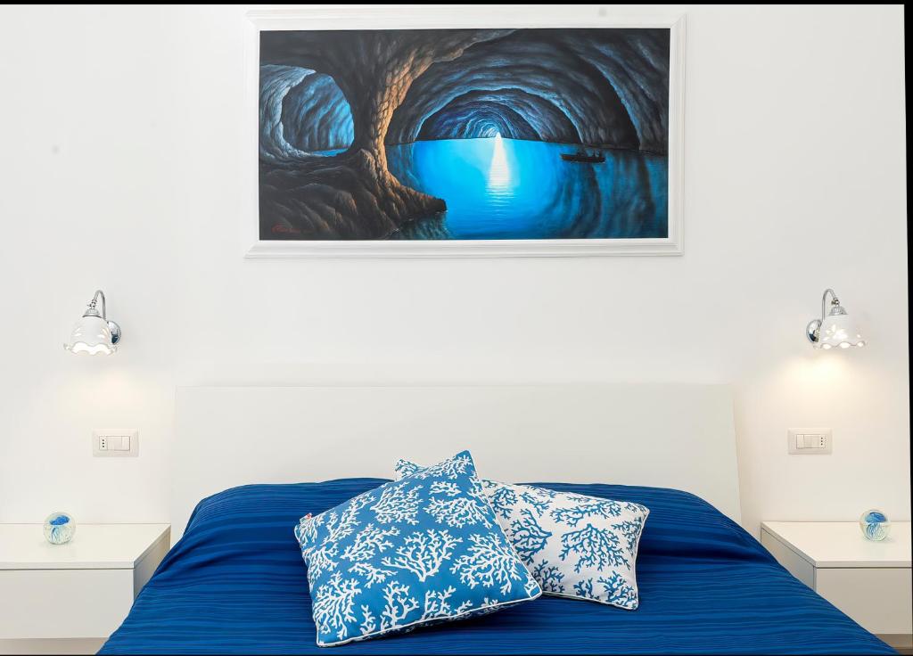 阿纳卡普里Caprita Guest House的卧室配有一张蓝色的床,墙上挂着一幅画