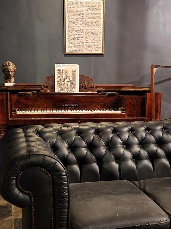 安特卫普Viktoria HOSTEL的客厅里设有钢琴和真皮沙发