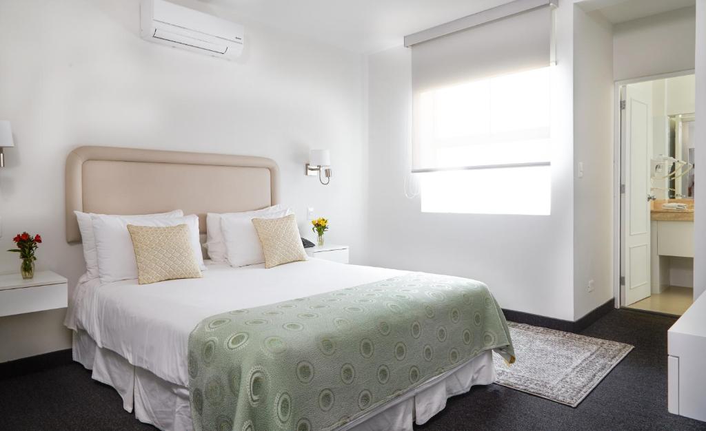 利马高尔夫精品酒店的白色卧室配有一张带绿毯的大床