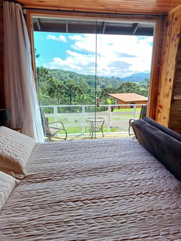乌鲁比西Recanto do Ipê cabana 01的一间卧室设有一张床和一个大窗户