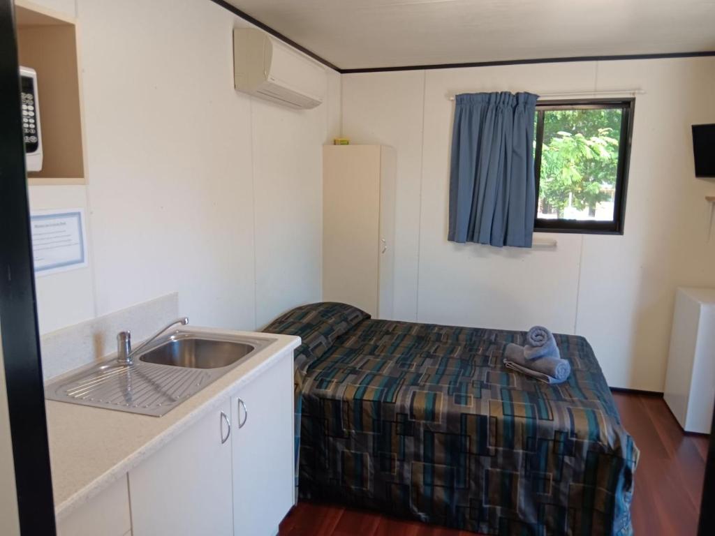 伊萨山Mt Isa Caravan Park的小房间设有水槽和一张床