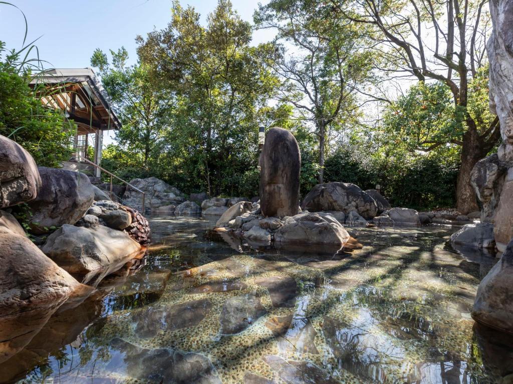 高知Tennenonsen Harunonoyu的花园中的一个池塘,里面设有岩石和雕像