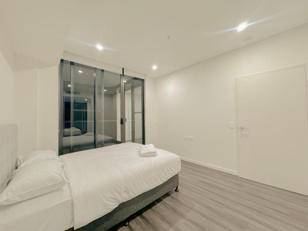 悉尼Burwood Cozy Apartment Free Parking的白色卧室设有床和大镜子