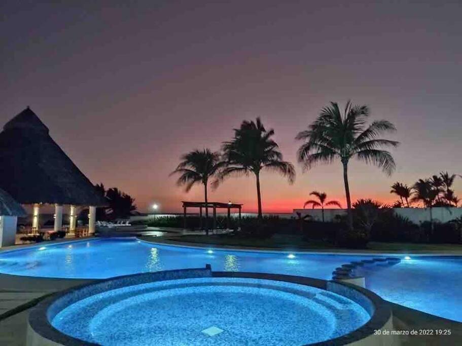 阿卡普尔科Hermoso Apartamento con club de playa的享有日落美景的度假游泳池