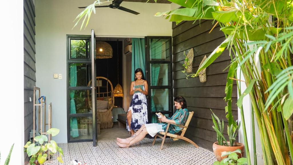 爱妮岛El Nido Boutique Vacation Villas的坐在房子门廊上椅子上的两名妇女