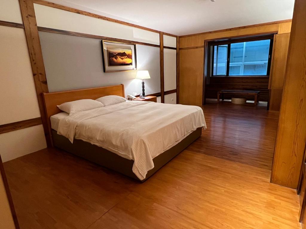 泰安乡錦水溫泉飯店的一间卧室设有一张大床,铺有木地板
