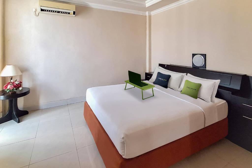 帕朗卡拉亚Urbanview Hotel Surya Kahayan Palangkaraya by RedDoorz的一间卧室配有一张大床和绿色椅子