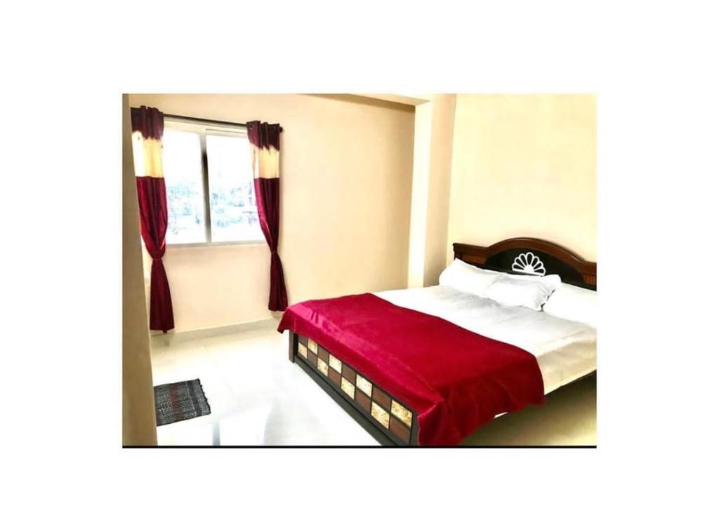 商沙巴Reef Hotel的一间卧室配有一张带红色毯子的床和窗户。