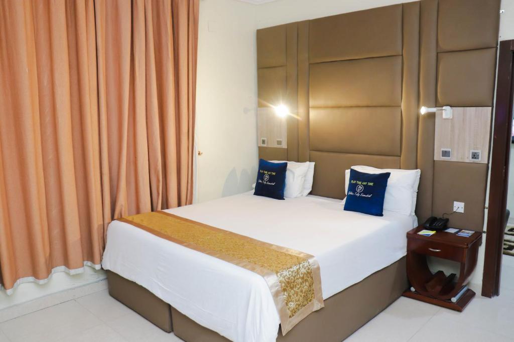 哈科特港Golden Tulip Hotel- Evergreen Port Harcourt的一间卧室配有一张带蓝色枕头的大床