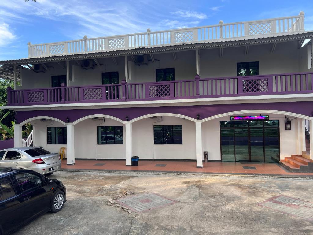 瓜埠OYO 90907 Brick Cottage Homes的一座紫色白色的建筑,停车场有停车位