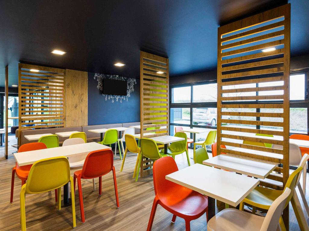 尚尼耶ibis budget Angoulême Nord的一间餐厅,房间内设有桌子和五颜六色的椅子