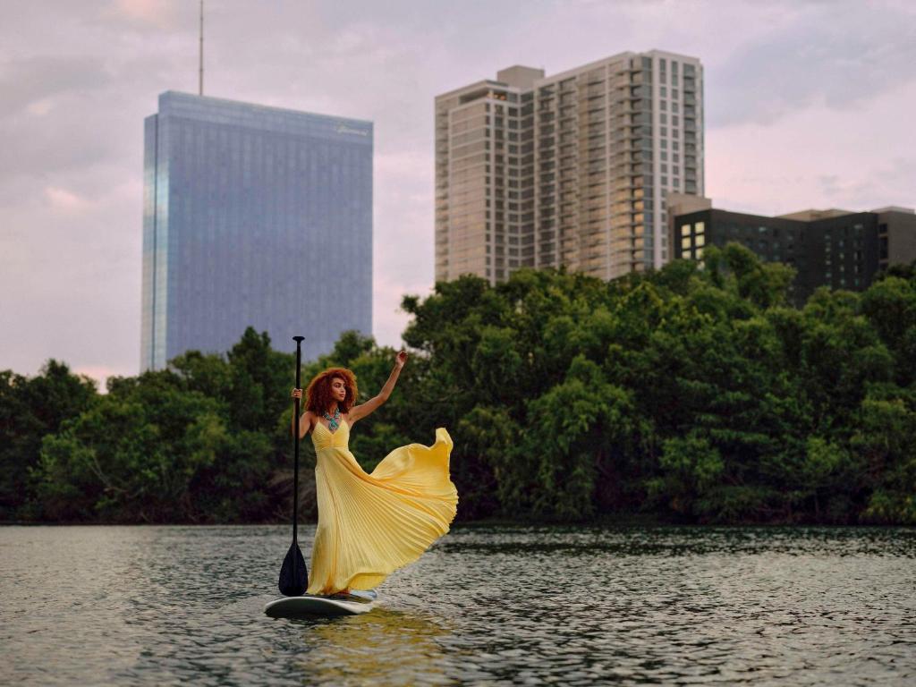 奥斯汀奥斯丁费尔蒙酒店的身着黄色衣服的妇女在水中桨板上