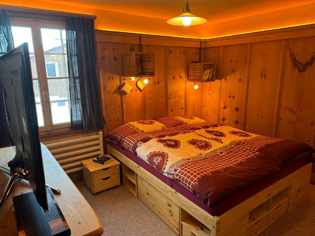 芙露姆赛山Flumserberg的卧室配有一张床铺,位于带木墙的房间内