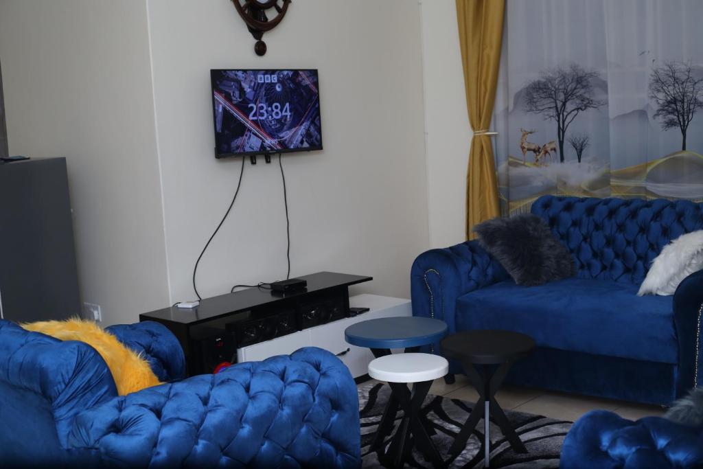 坎帕拉pettan Appartment的客厅配有2张蓝色沙发和电视
