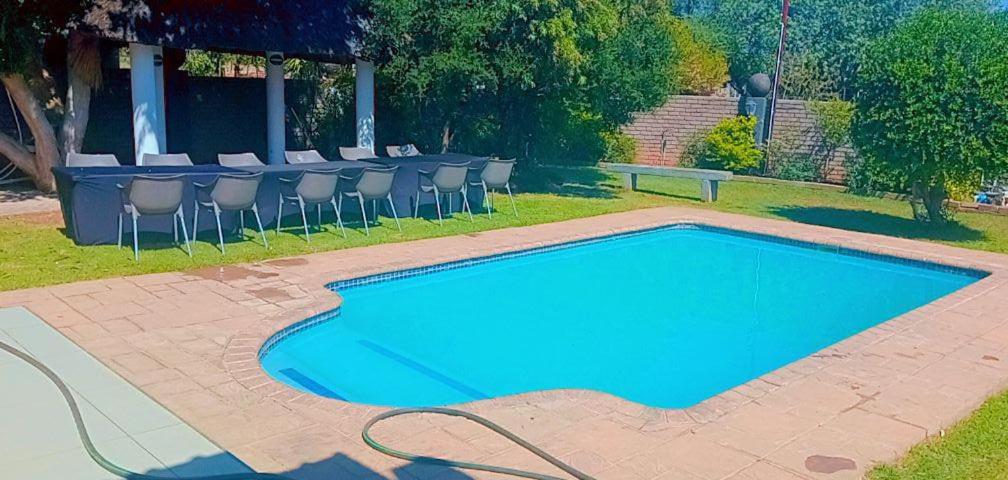 金伯利Boontjieskraal的蓝色的游泳池配有椅子和桌子