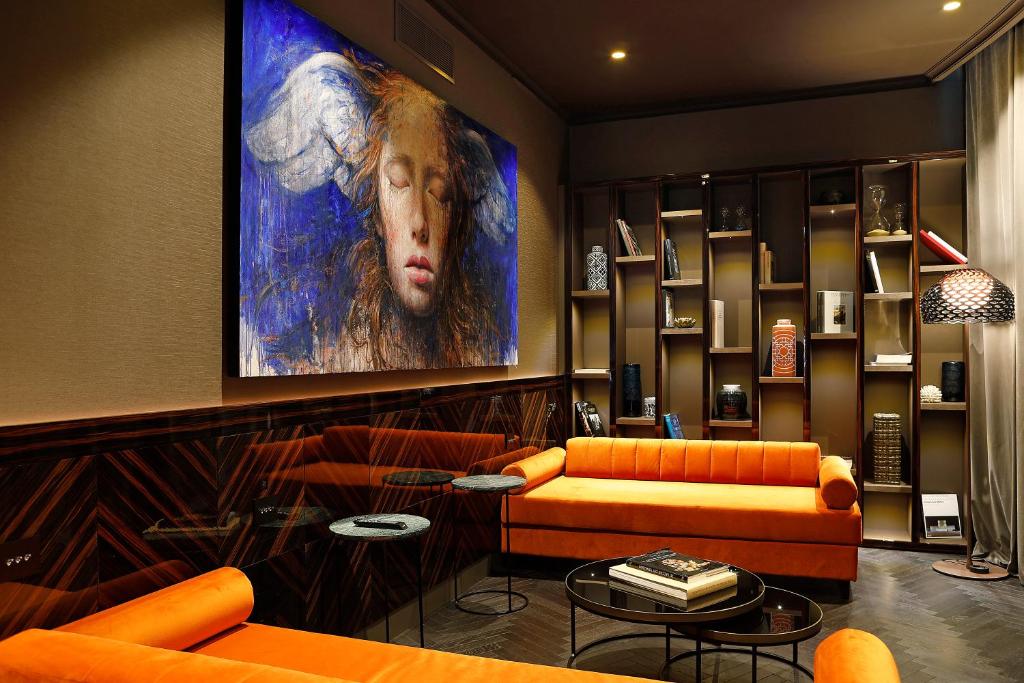 罗马U-Visionary Roma Hotel的客厅配有橙色家具和大画作