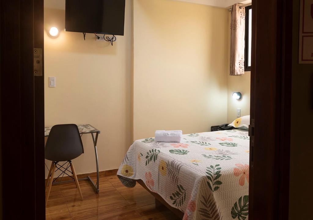 利马Hotel Precursores的卧室配有1张床、1张桌子和1把椅子