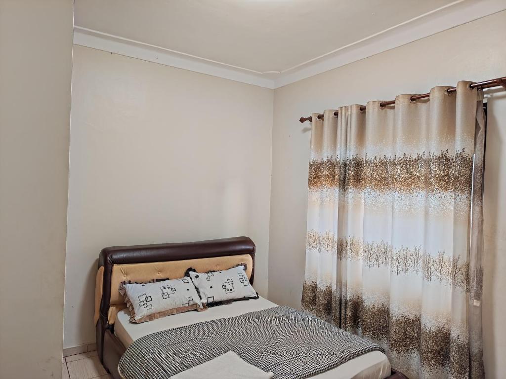 NamugongoTwinkle Blue Inn的一间卧室配有床和窗帘