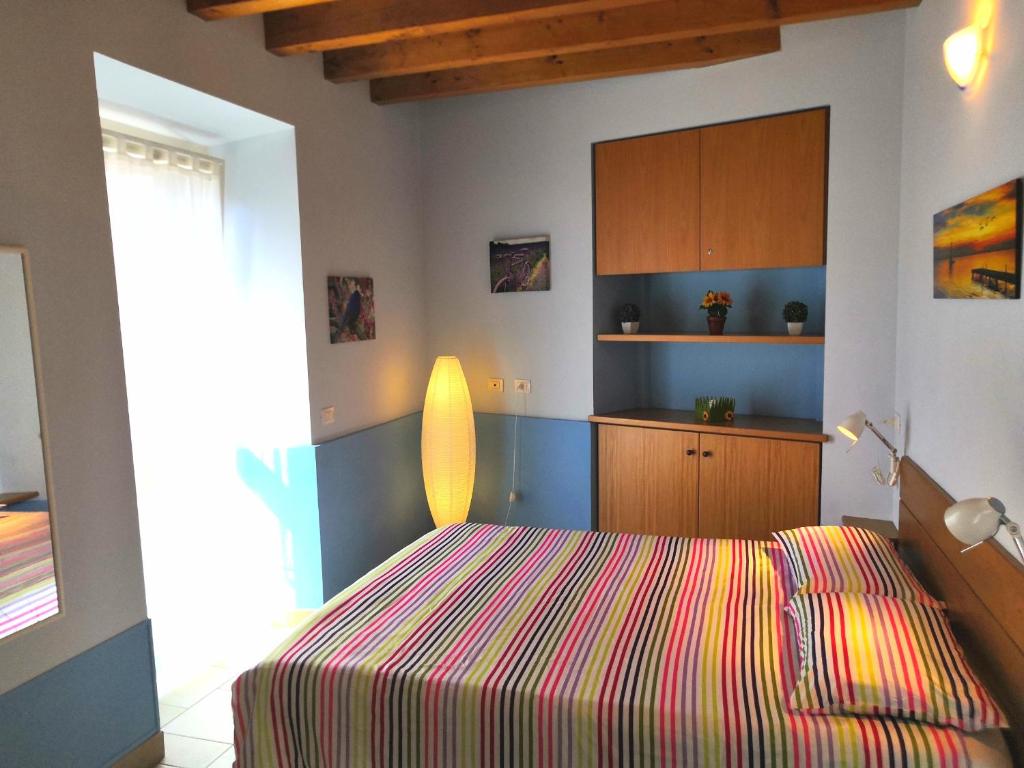 韦尔巴尼亚Residenza Silvana Apt Cielo and Apt Giardino on the ground floor with parking的一间卧室配有一张带彩色条纹毯子的床