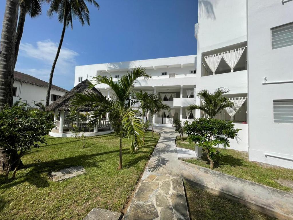 瓦塔穆Watamu Ascot Hotel的享有棕榈树白色建筑的外部景色