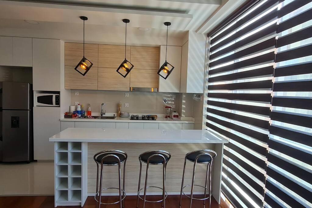 拉巴斯departamento de 2 dormitorios的厨房配有带三把凳的柜台