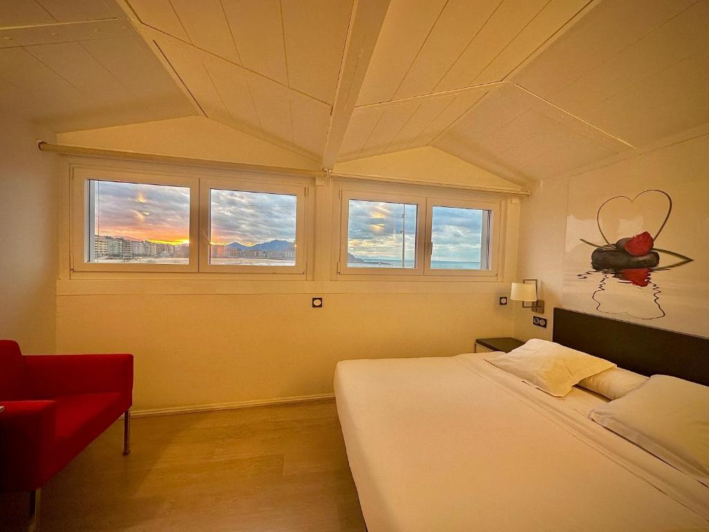 圣塞瓦斯蒂安Hotel Punta Monpas的一间卧室设有床、窗户和红色椅子