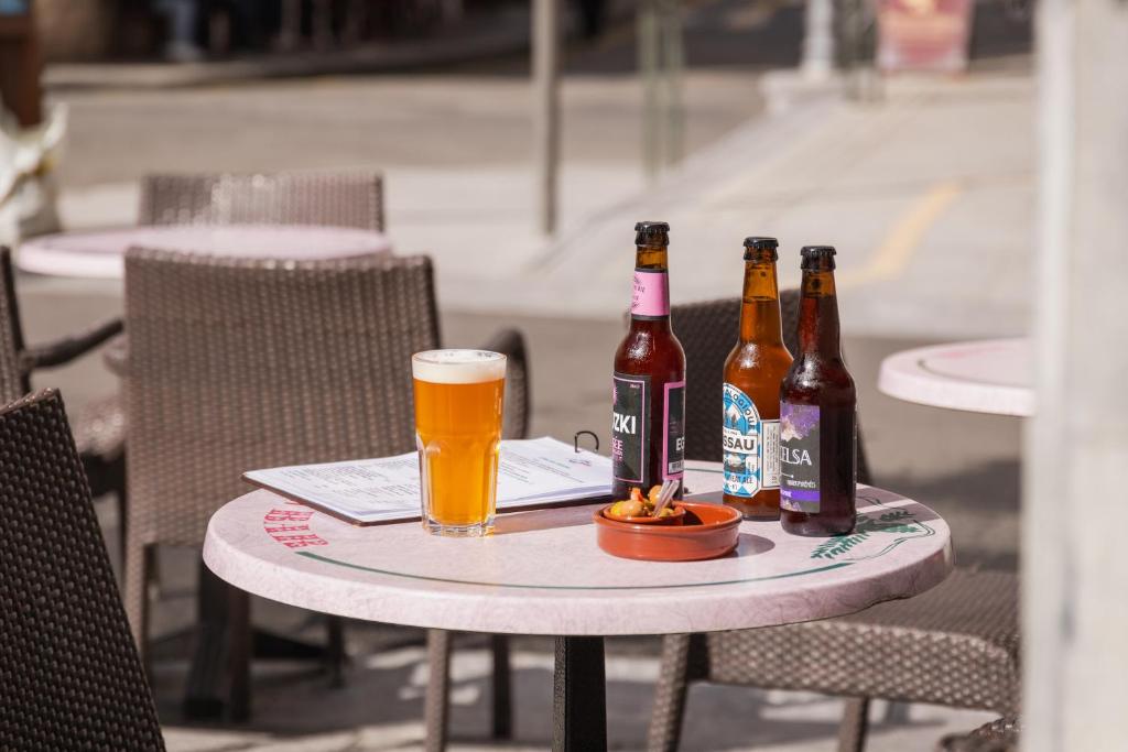 科特雷布瓦琳酒店 的一张桌子,上面放着三瓶啤酒和一杯啤酒