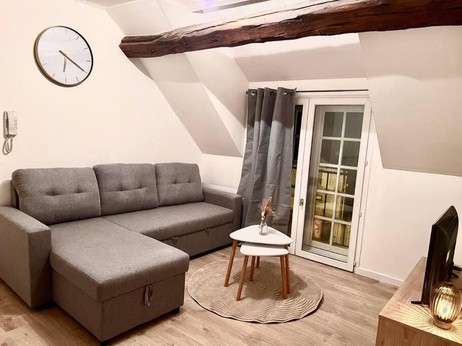 讷穆尔Appartement Cosy Nemours的客厅配有沙发和墙上的时钟