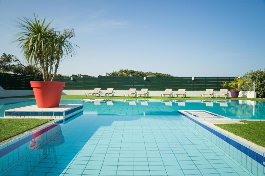 安格雷亚特兰塔尔酒店的游泳池旁设有椅子和棕榈树