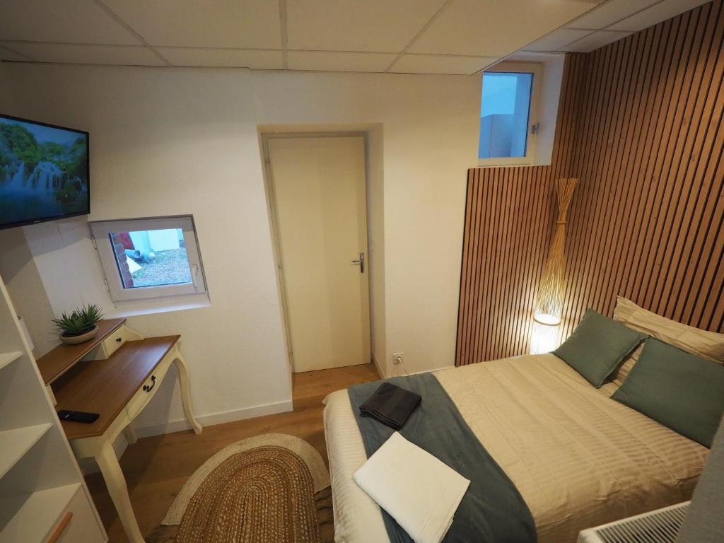 日安Appartement meublé 4 - 15 min Dampierre - 25 min Belleville - WIFI的一间卧室配有一张床、一张书桌和一台电视