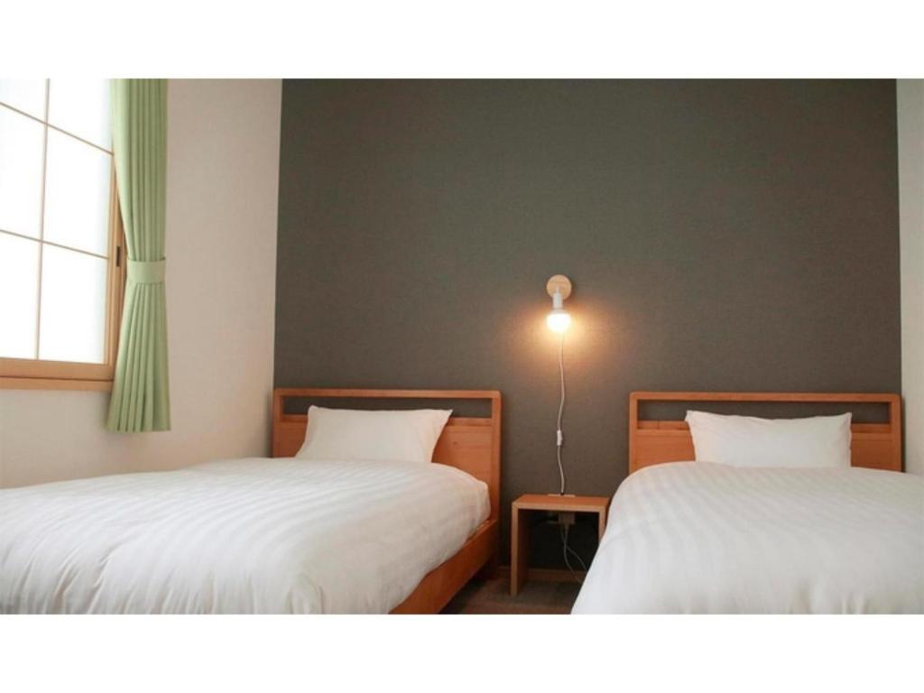 稚内THE STAY WAKKANAI - Vacation STAY 40679v的客房设有两张床和窗户。