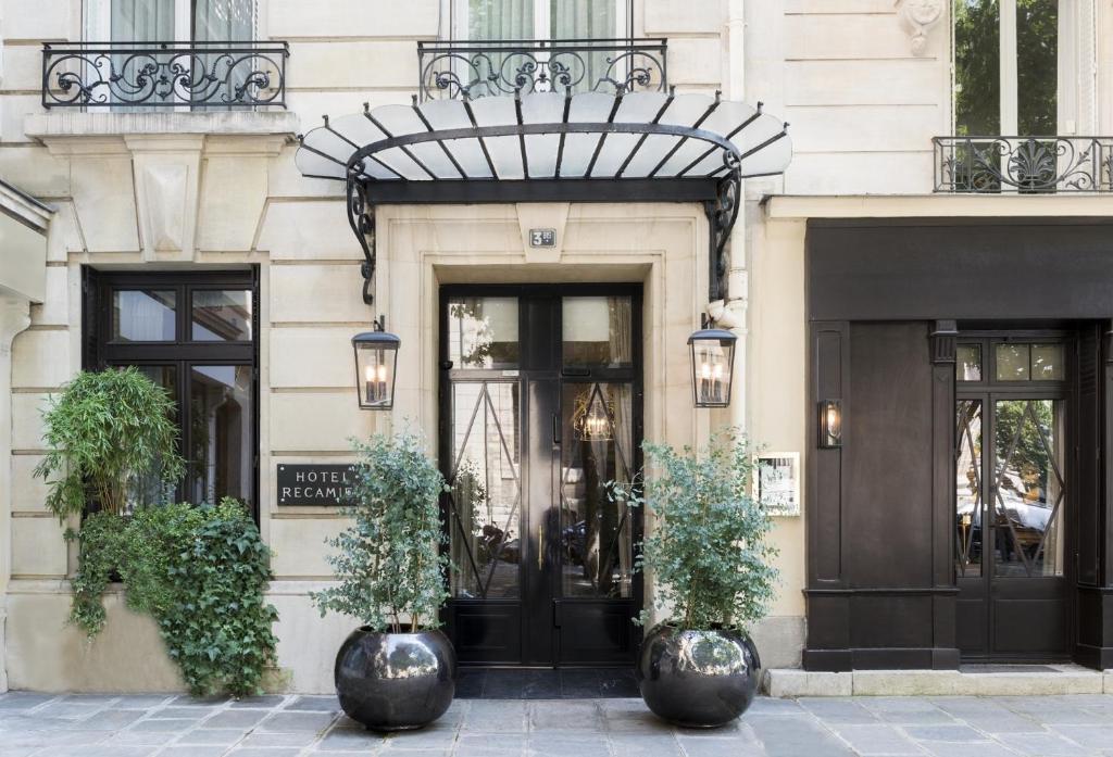 巴黎贵族酒店的一座有两棵盆栽植物的黑色门的建筑