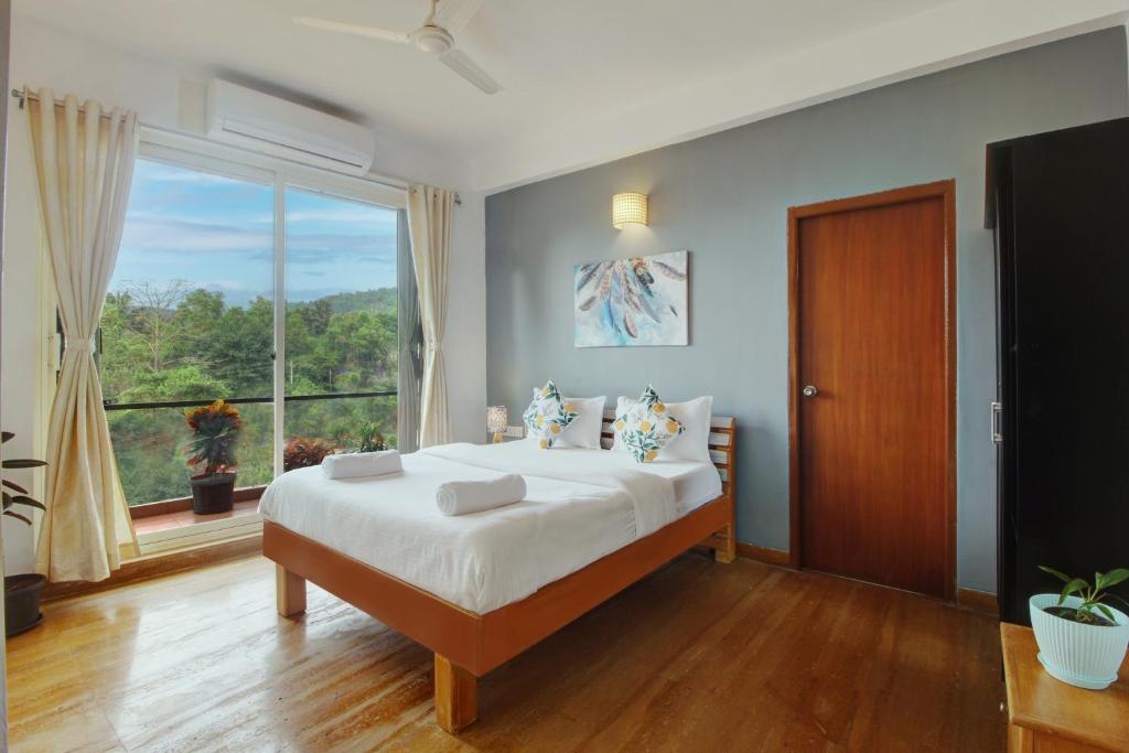 安君纳Genesis Leisure - Charming home-stays near Anjuna, Vagator & Assagao的一间卧室设有一张大床和一个大窗户