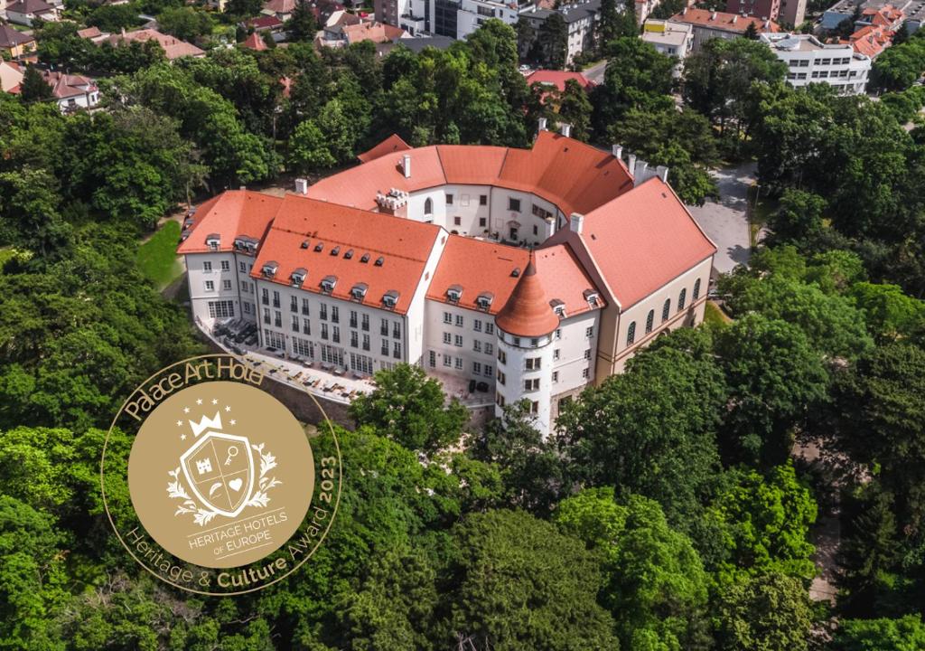佩济诺克Palace Art Hotel Pezinok的一座大建筑,树上有一个红色屋顶