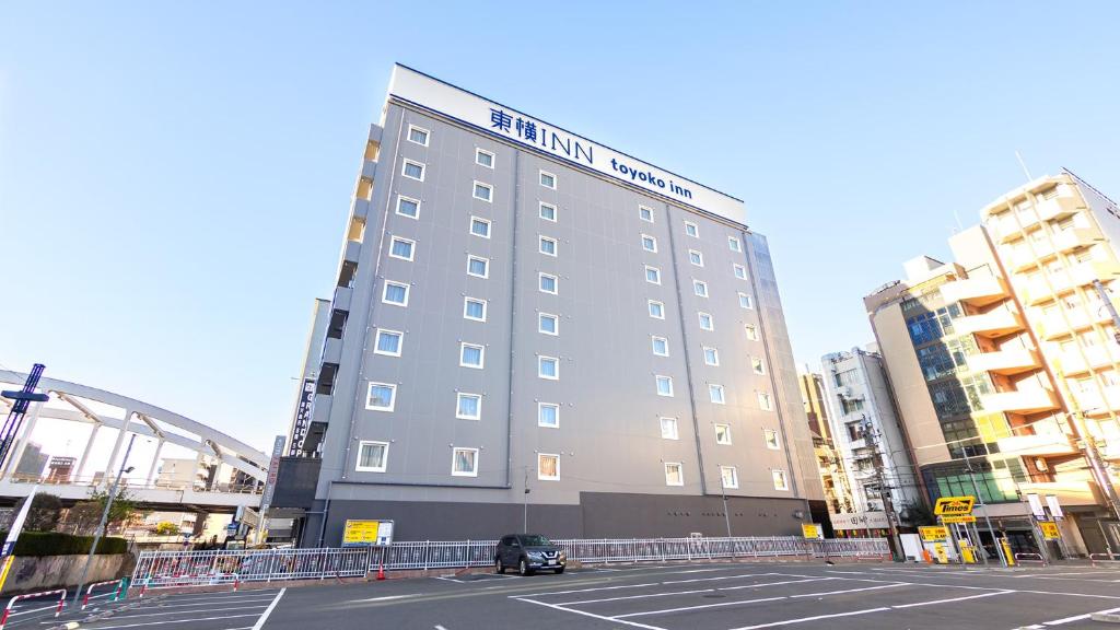 横滨Toyoko Inn Yokohama-eki Nishi-guchi的一座高大的建筑,前面有一辆汽车