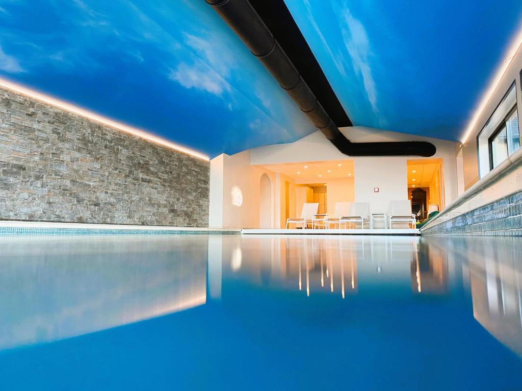 翁弗勒尔安塔尔温泉酒店的一个带蓝色天花板的游泳池
