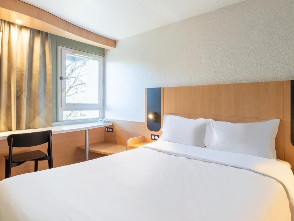 布隆B&B HOTEL Lyon Eurexpo Bron的一间卧室配有一张床、一张书桌和一个窗户。
