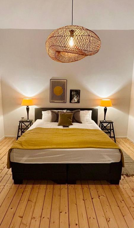 波鸿FeelsLikeHome - Stylische und zentrale Altbauwohnung mit Terrasse&Garten的一间卧室配有一张大床和一个吊灯。