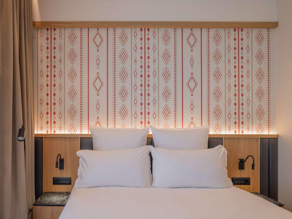 普里什蒂纳Mercure Prishtina City的卧室内的一张带两个白色枕头的床