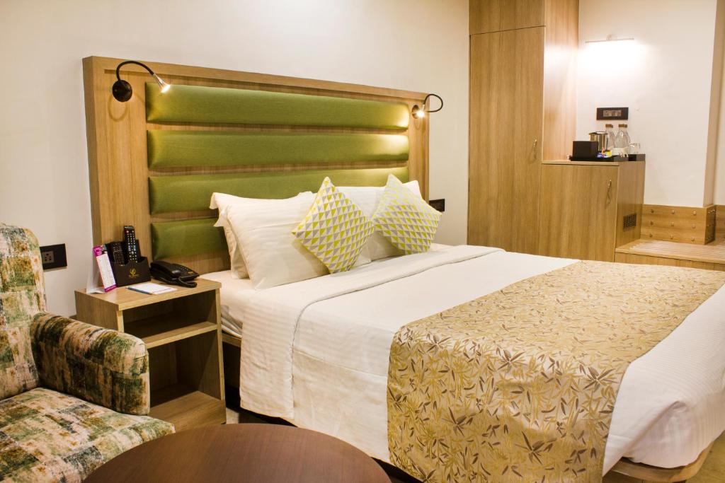 孟买Regenta Place The Emerald的酒店客房带一张大床和一把椅子