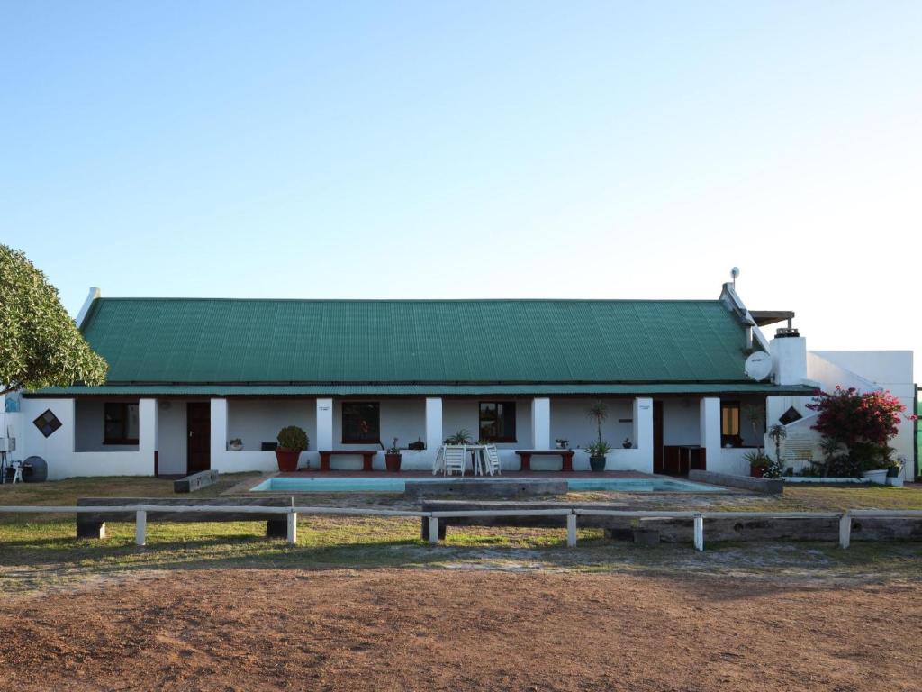 伊泽芳登Tula Guest Farm的白色的建筑,有绿色的屋顶和长椅