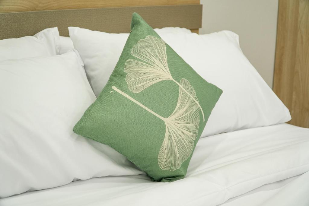 Ban Dam Phraเมตตา เรสซิเด้นซ์ - Metta Residence的床上的绿色枕头和白色枕头