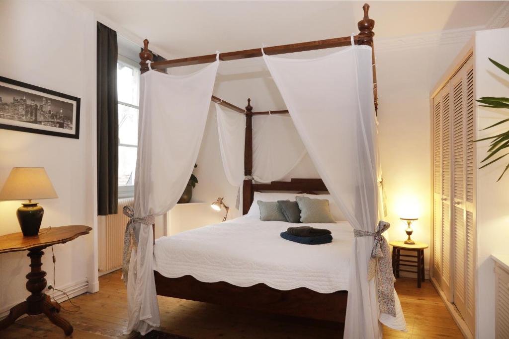 桑利斯Appartements 4 vents by La Boîte En Plus的一间卧室配有一张带窗帘的四柱床