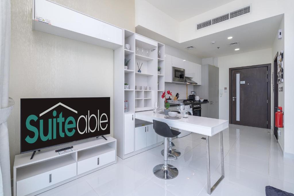迪拜Placid Studio close to Dubai Miracle Garden的白色的厨房配有桌子和电视。