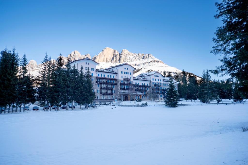 卡雷扎湖Grand Hotel Carezza Multiproprietà的一座大建筑,位于雪覆盖的山前