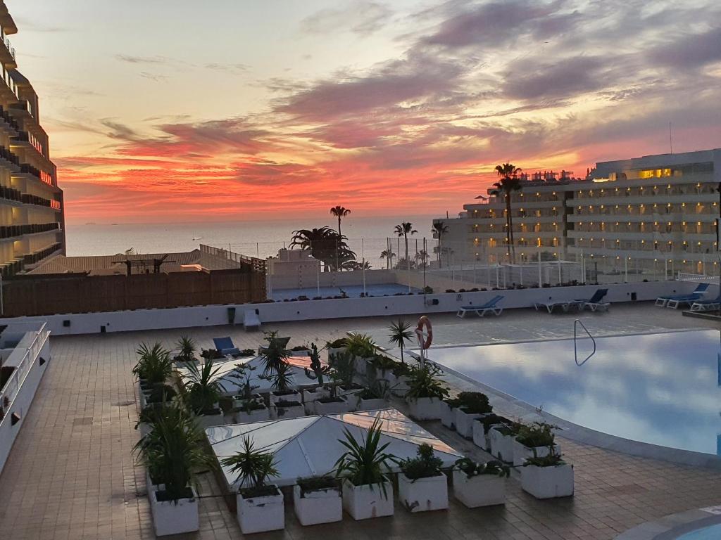 阿德耶Royal Park Torviscas Beach的享有酒店游泳池的景色和日落美景