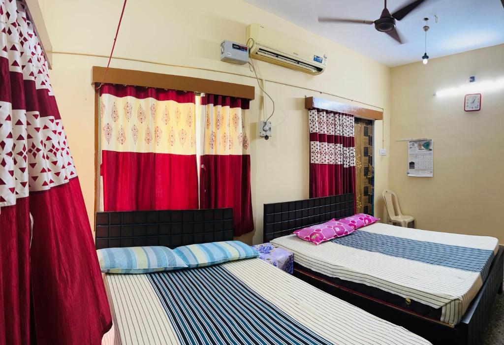 PerambalūrSirvachur madhurakalli amman guest house的配有红色窗帘的客房内的两张床