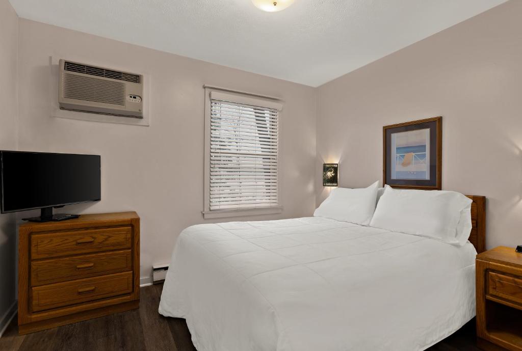 特拉弗斯城特拉弗斯湾宾馆的卧室配有白色的床和平面电视。