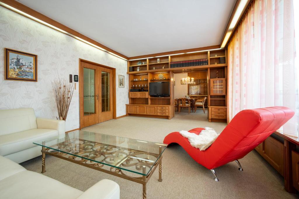 因斯布鲁克Innsbruck Garden Residence的客厅配有红色椅子和玻璃桌