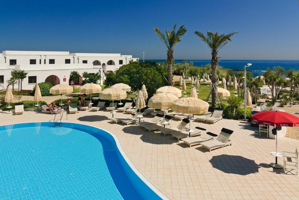 滨海波利尼亚诺皮埃特拉布鲁Spa度假酒店 - CDS酒店的一个带游泳池、遮阳伞和椅子的度假村